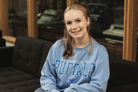 Photo of Libraries' student assistant Sophia Finger sitting on the couch in Special Collections. 