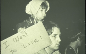 Young girl holds "I Want to Live" poster during Love Canal disaster. 