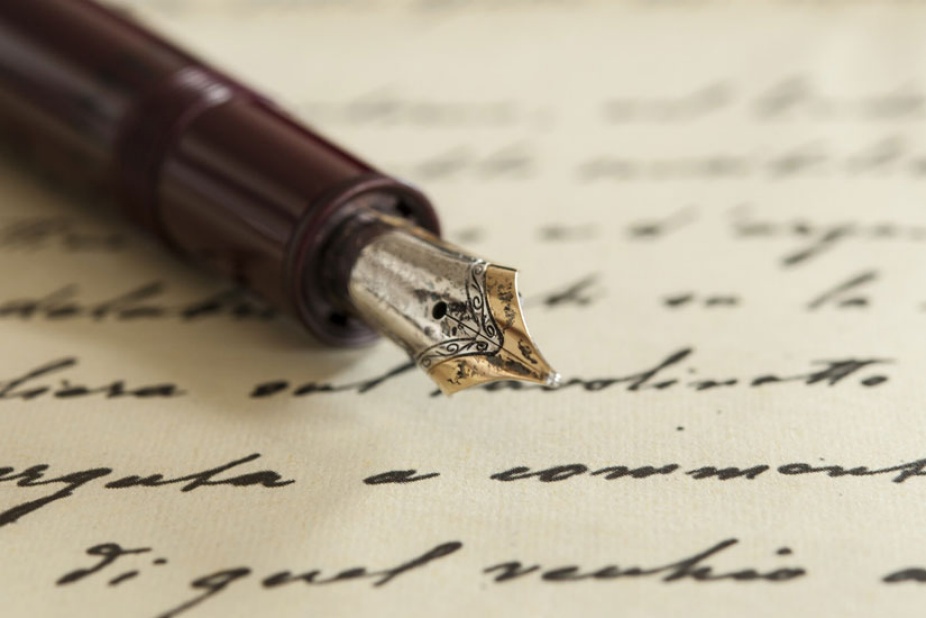 Fountain pen on a paper with cursive writing.