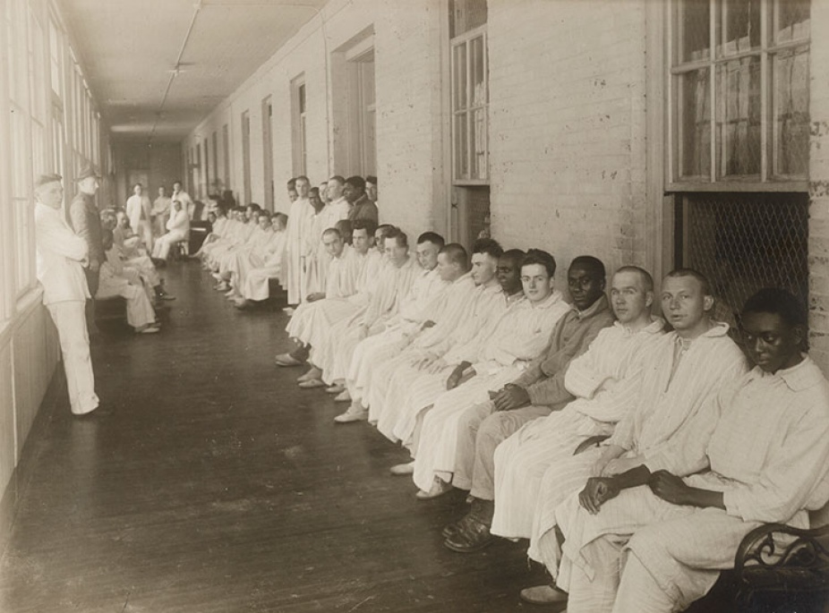 In black and white, a group of patients is in the solarium. 