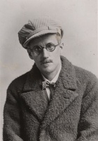 James Joyce wearing a coat, glasses and hat. 