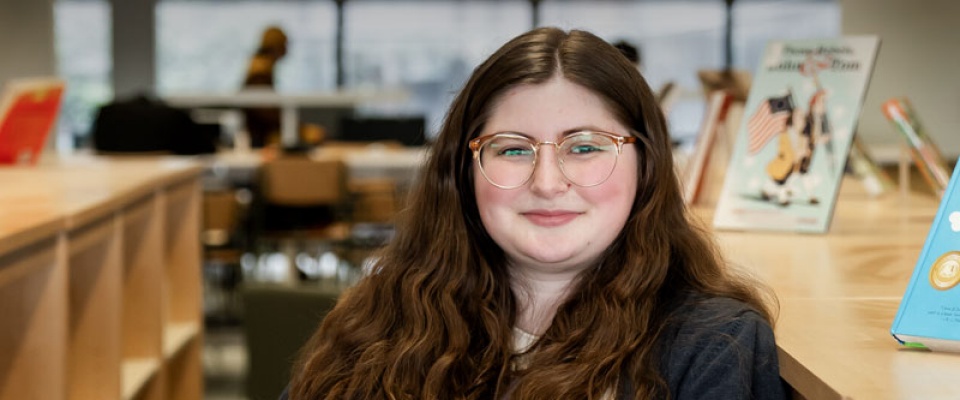 UB Libraries student assistant Corina Carr, shown in Lockwood Memorial Library, earned a master’s degree in information and library science in May 2025. 
