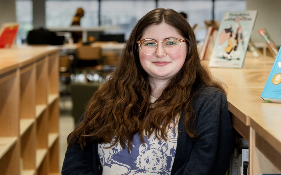 UB Libraries student assistant Corina Carr, shown in Lockwood Memorial Library, earned a master’s degree in information and library science in May 2025. 