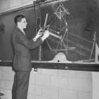Black and white old photo of a UB student using a chalkboard for his studies. 